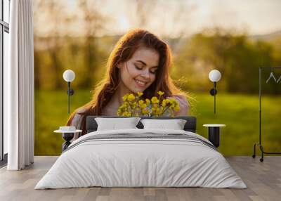 portrait of a happy woman with a bouquet of yellow flowers illuminated from the back by the setting sun Wall mural