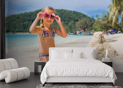 cute little girl in sunglasses and a swimsuit on the beach in paradise by the sea. Travel and Vacation. Freedom Concept Wall mural