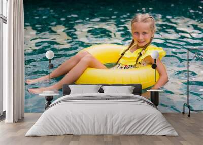 Happy little girl with inflatable rubber circle having fun in swimming pool Wall mural