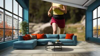 A woman is running in a field with a hat on Wall mural