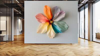 A beautifully crafted flower with petals in a gradient of vibrant colors displays artistic elegance against a soft background. Wall mural