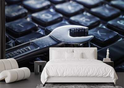 A shiny, metallic wrench placed on a sleek, black laptop keyboard, symbolizing tech support and the fusion of manual and digital tools. Wall mural