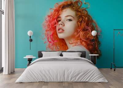 A young person with vividly colorful curly hair poses confidently against a bright turquoise background, capturing a bold, expressive moment. Wall mural