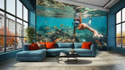 Boy snorkeling in a transparent ocean watching colorful fish Wall mural