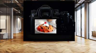 DSLR camera or mirrorless body lit by a rim light showing a papaya breakfast on the back of the camera display. Low key light photography Wall mural