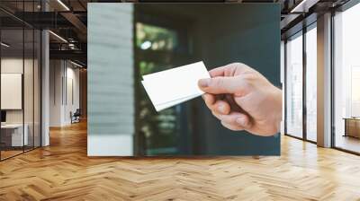 Mock Up business cards in the hand of man, against the background of the office - the company's store. Concept on the topic of Business. Wall mural