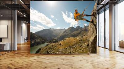 Person climbing in high mountains with yellow jacket rope and helmet in nature, confidence and risk, safety Wall mural