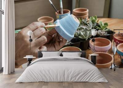 Hands of a Latin  woman, painting clay pots to plant succulent plants Wall mural