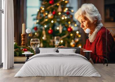 Sad senior woman having dinner alone at home on Christmas Eve night Wall mural