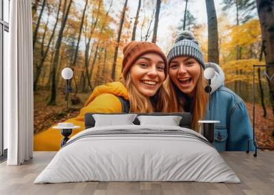 Two funny girls taking a selfie in a forest in autumn Wall mural