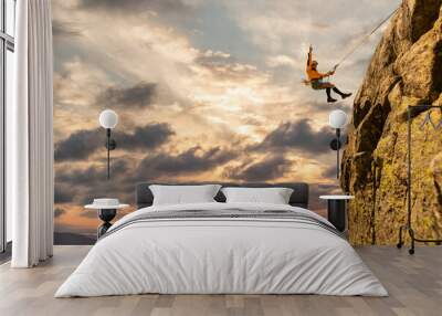 Woman climbing at sunset on mountain golden colors, feeling security and confidence Wall mural