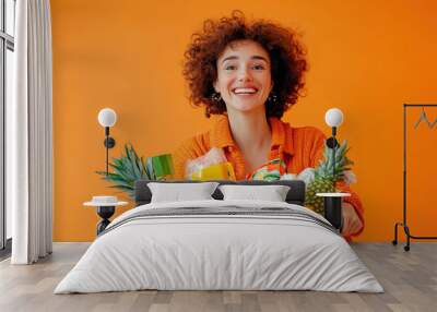 Young woman with a shopping cart full of products isolated on orange Wall mural