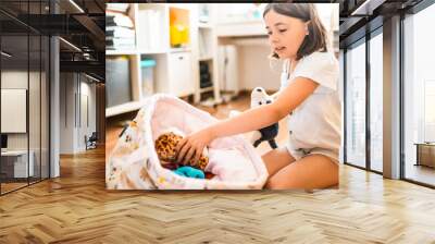 Child cleans up her toys in the room.   Wall mural