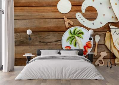 Creative meal for a child, strawberries and banana, funny food over wooden background. Fruits for baby. Top view, flat lay Wall mural