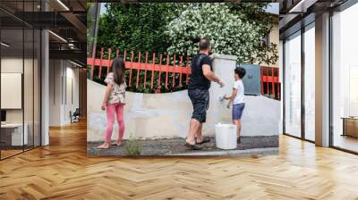 father with two daughters painting the house fence Wall mural