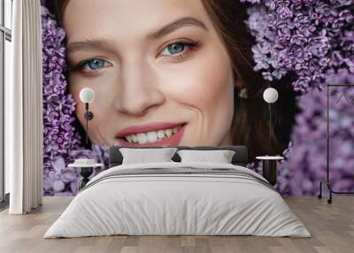 Close up beauty portrait of young beautiful happy smiling woman with healthy flawless radiant skin, natural makeup, posing with blooming lilac flowers. Copy, empty space for text Wall mural