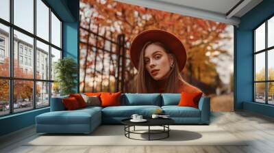 Outdoor close up autumn portrait of young elegant woman wearing stylish orange hat, trendy round earrings, posing in street. Copy, empty space for text Wall mural