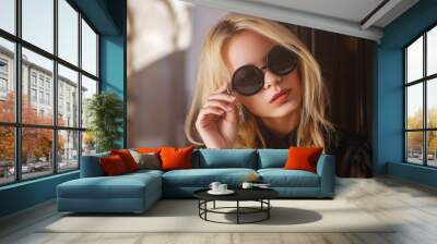 Outdoor close up portrait of young beautiful fashionable woman wearing black round sunglasses, blouse, posing in street of european city. Female fashion concept. Copy, empty space for text Wall mural