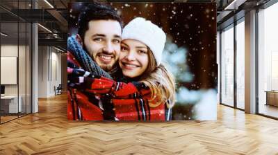 Outdoor close up portrait of young beautiful happy smiling couple. Models looking at camera, bundled up in tartan blanket . Christmas, new year, winter holidays, dating concept. Copy space for text  Wall mural