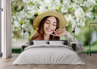 Outdoor close up portrait of young beautiful happy smiling girl with healthy white teeth,  radiant skin, long natural hair. Model posing in flowering garden. Beauty, health care concept.  Wall mural