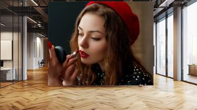 Young elegant woman doing her makeup with red lipstick Wall mural