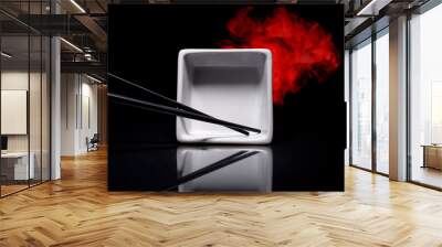 Stainless steel chopsticks on white square bowl on black background. Wall mural