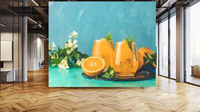 Two glasses of orange ice drink with fresh mint on wooden turquoise table surface. Fresh cocktail drinks with ice fruit and herb decoration. Alcoholic non alcoholic beverage, summer fresh drink Wall mural