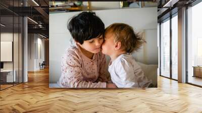 portrait of little sister kissing elder sibling Wall mural