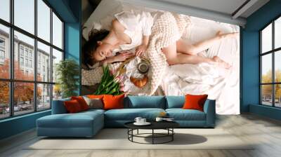 Pretty young woman is having breakfast in bed bedroom. Coffe and croissant are served on the golden tray. Woman is enjoying her morning in beautiful interior. She is happy and relaxed. Bride. Wall mural