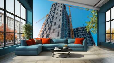 Tall building in construction. Construction site and cranes. Unfinished residential building. Wall mural