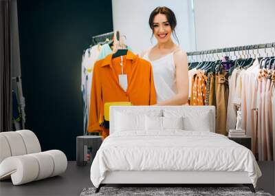 Perfect combinations of dress and bag! Beautiful young woman trying to choose clothes to herself or customer while working in the fashion boutique. Fashion stylist show new collection and in store Wall mural