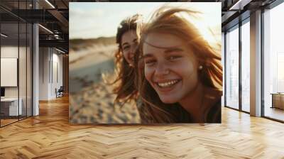 Two cheerful young women smiling and having fun on the beach at sunset. They are enjoying a carefree and happy moment together. Wall mural