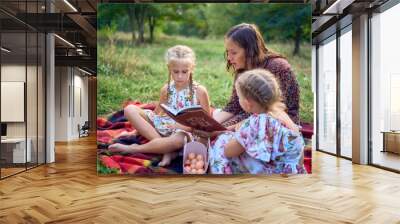 a mother and her two daughters read the holy bible and pray at an Easter picnic Wall mural