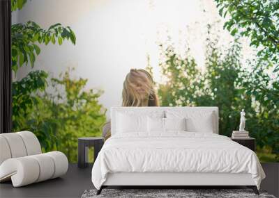 a portrait of a teenage girl with long blond hair in a sunlit garden Wall mural