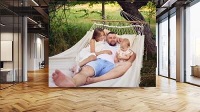 dad playing with his daughters, baby and teenager in a hammock Wall mural