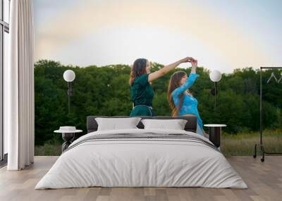 two woman in  whimsical aesthetic style dress  dance in a field in the summer at a sunset Wall mural