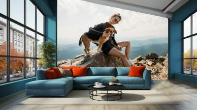 sporty young woman with a dog on top of the mountain Wall mural