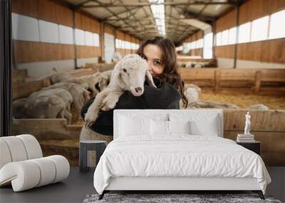 young happy woman on a sheep farm hugging with sheep Wall mural