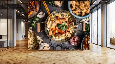 Asian kitchen table with food bowls, wok , stir fry , chopsticks and ingredients on background, top view Wall mural