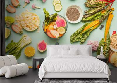 Healthy food ingredients flat lay with various fruits , vegetables, seeds and nut on light mint background. Mixer for detox drinks making, top view. Dieting and clean eating concept Wall mural