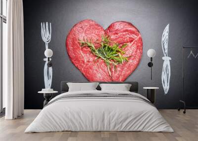 Heart shaped raw chop of meat. Meat love with  painted cutlery:  fork and knife. Dark chalkboard background . For Meat lovers and eater Wall mural