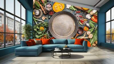 Various Healthy and organic harvest vegetables and ingredients: pumpkin, greens, tomatoes,kale,leek,chard,celery around empty cooking pot for tasty Thanksgiving seasonal cooking, top view, frame Wall mural