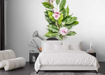 Watering can with gardening tools and green bunch of twigs with blossom decoration on white desk background, top view Wall mural