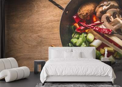 Wok pot with vegetarian asian cuisine ingredients for stir fry with chopped vegetables, spices, sesame seeds and chopsticks on rustic wooden background, top view. Chinese or Thai food cooking concept Wall mural