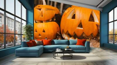 garden with carved halloween orange pumpkin decoration, jack o lantern with spooky faces on porch. Halloween jack-o-lantern on autumn leaves Wall mural