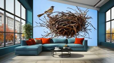 A unique image of a bird perched on a large nest suspended in mid-air against a clear blue sky. The minimalist composition and the intriguing subject create a sense of wonder and curiosity, making it Wall mural