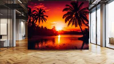 Vibrant red and orange hues fill the sky as the sun sets behind silhouetted palm trees, reflecting on calm waters. This tranquil tropical scene evokes a sense of serenity and natural beauty. Wall mural