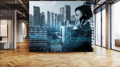 Attractive black businesswoman pensively processing conference call by phone to find financial solution for venture capital project. Hologram chart over Bangkok city background Wall mural