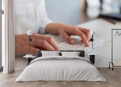 Woman hands, fingers typing on white wireless keyboard lying on marble office table desk, side view. Closeup of texting a letter, no face. Concept of work Wall mural