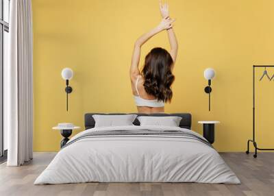 Back view attractive slim young brunette woman 20s wearing white underwear thong with perfect skinny fit body standing posing raise up hands isolated on plain yellow color background studio portrait Wall mural